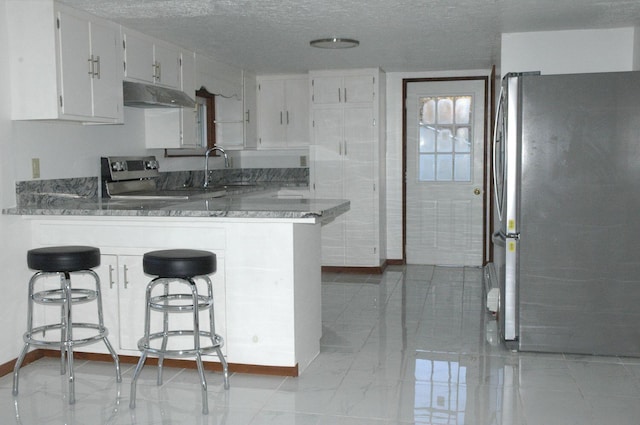 kitchen with sink, kitchen peninsula, white cabinetry, appliances with stainless steel finishes, and a kitchen breakfast bar