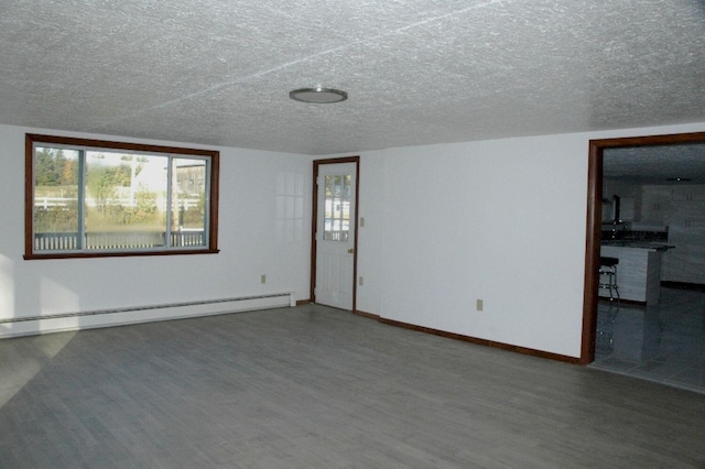 spare room featuring a textured ceiling, baseboard heating, and hardwood / wood-style floors