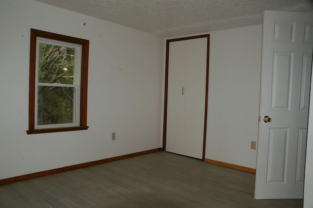 unfurnished bedroom with a textured ceiling, light wood-type flooring, and a closet