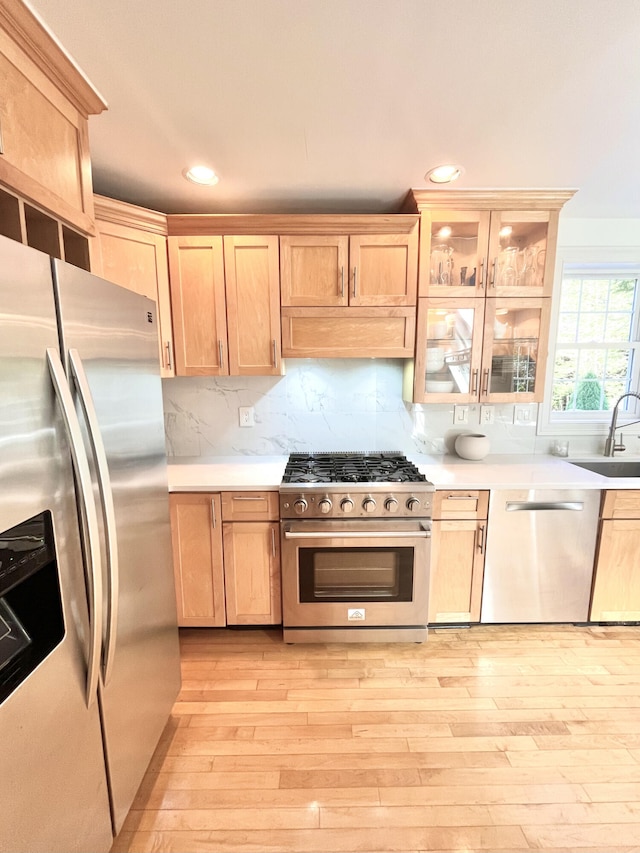 kitchen featuring decorative backsplash, light brown cabinets, stainless steel appliances, sink, and light hardwood / wood-style flooring