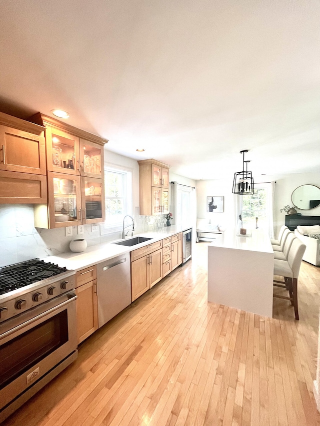 kitchen featuring light hardwood / wood-style floors, tasteful backsplash, decorative light fixtures, sink, and stainless steel appliances