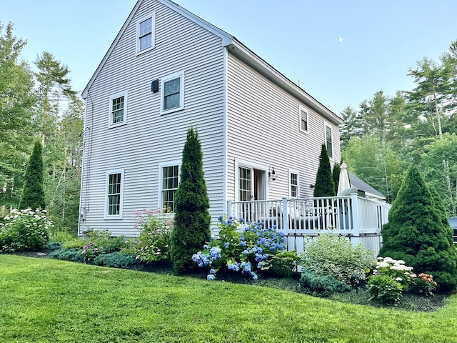 back of property featuring a deck and a lawn