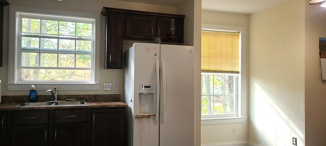 kitchen featuring dark brown cabinetry, sink, and white refrigerator with ice dispenser