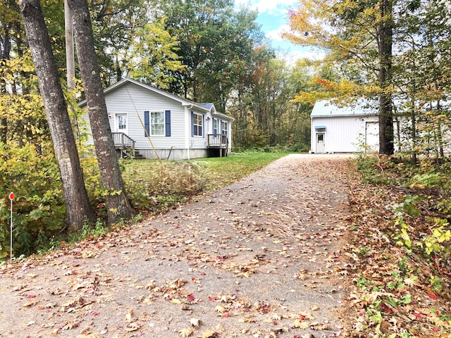 view of home's exterior with driveway and an outbuilding