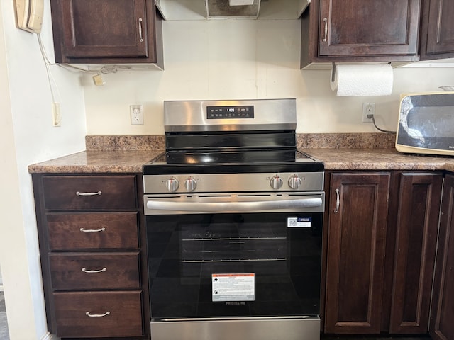 kitchen featuring dark brown cabinetry, wall chimney exhaust hood, and electric stove
