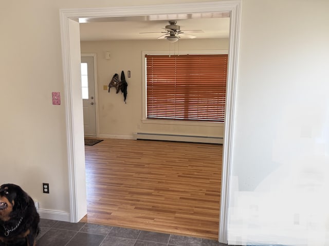 hallway with dark wood-type flooring, baseboards, and a baseboard heating unit