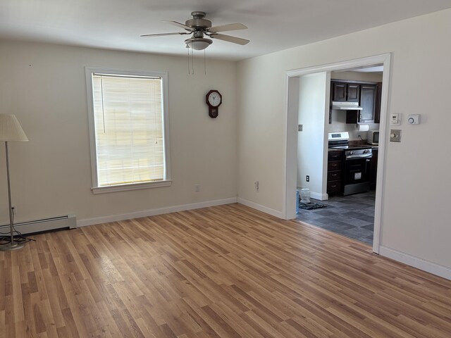 empty room featuring ceiling fan, baseboards, light wood finished floors, and a baseboard heating unit