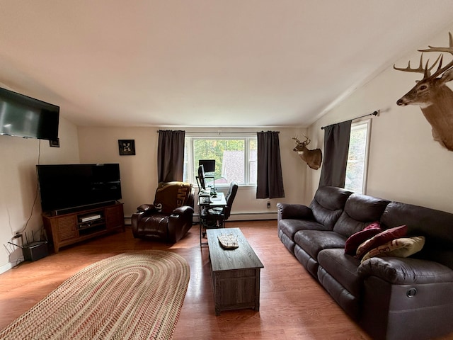 living room featuring wood-type flooring, vaulted ceiling, and a baseboard heating unit