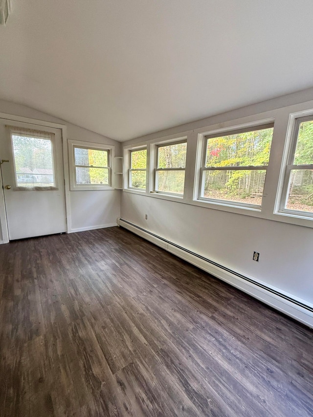 empty room featuring a baseboard radiator, vaulted ceiling, dark wood-type flooring, and a wealth of natural light