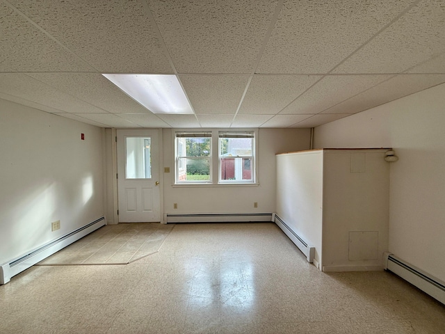 empty room featuring a paneled ceiling and a baseboard heating unit