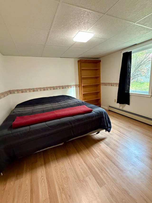 bedroom with baseboard heating, a paneled ceiling, and hardwood / wood-style floors