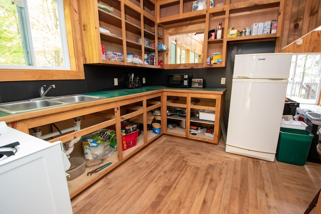 kitchen with white refrigerator, parquet flooring, and sink