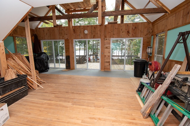 living room with high vaulted ceiling, light wood-type flooring, beam ceiling, and a healthy amount of sunlight