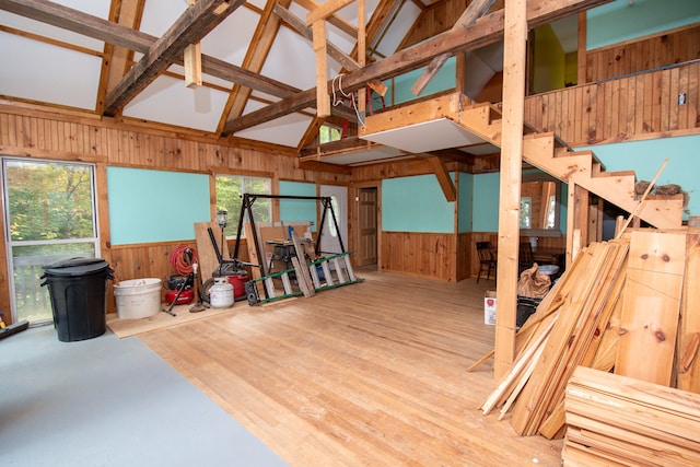 misc room featuring high vaulted ceiling, a wealth of natural light, wood-type flooring, and wooden walls