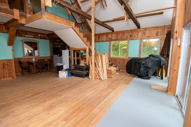 living room featuring vaulted ceiling with beams, wooden walls, and hardwood / wood-style floors