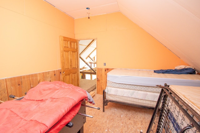 bedroom featuring lofted ceiling and wood walls