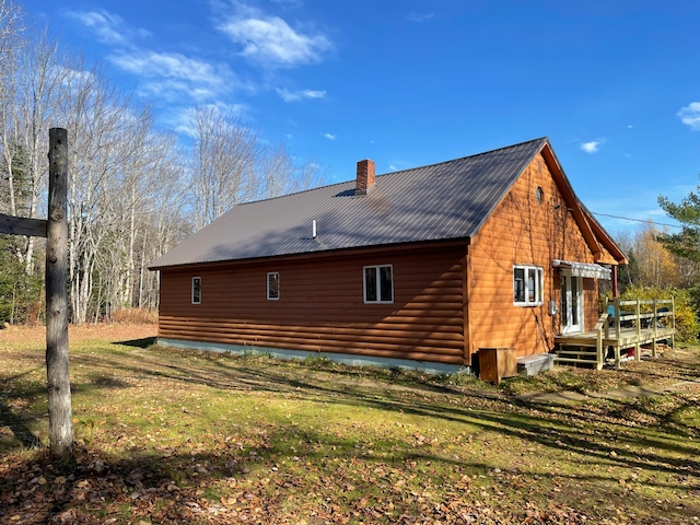 back of property featuring a wooden deck and a lawn