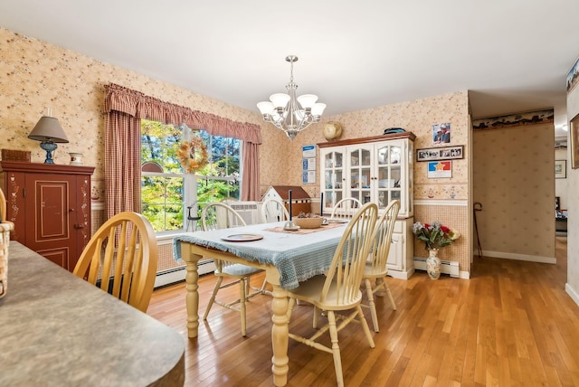 dining area with light hardwood / wood-style flooring, baseboard heating, and a chandelier