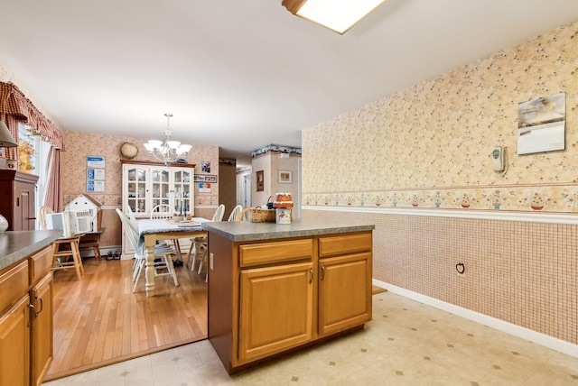 kitchen with light hardwood / wood-style floors, a chandelier, a kitchen island, and hanging light fixtures