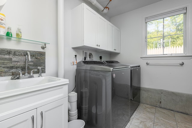 washroom featuring washing machine and dryer, cabinets, and sink