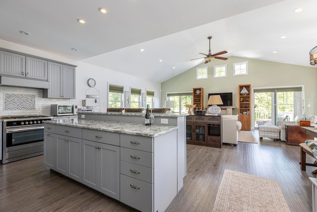 kitchen featuring gray cabinets, stainless steel appliances, a kitchen island with sink, and dark wood-type flooring