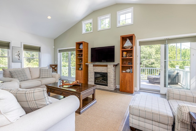 living room featuring lofted ceiling, a stone fireplace, and light wood-type flooring