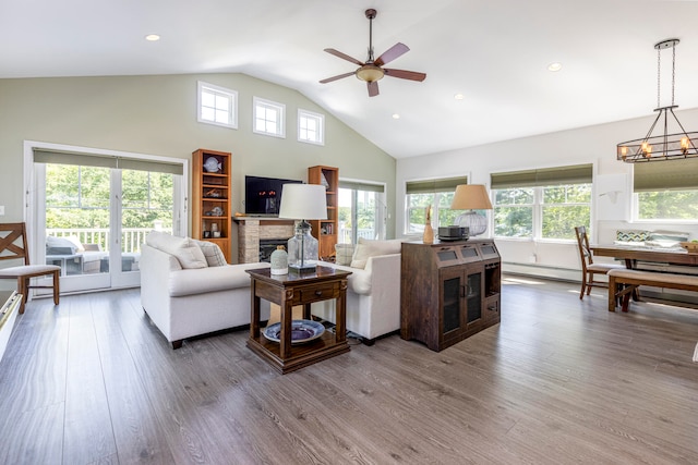 living room with hardwood / wood-style flooring, ceiling fan with notable chandelier, high vaulted ceiling, and a healthy amount of sunlight