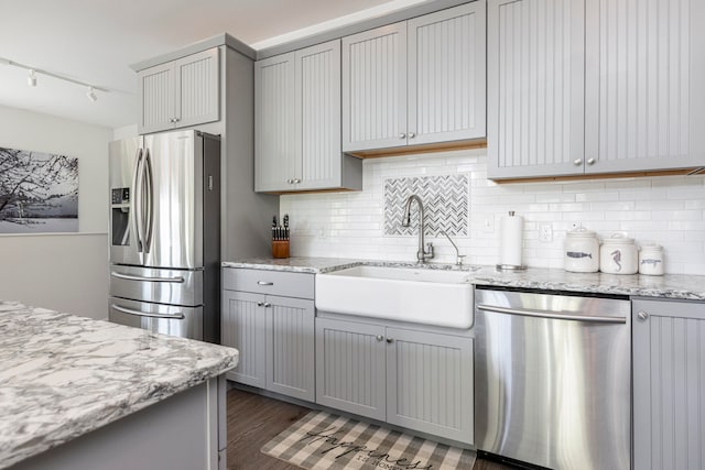 kitchen with light stone counters, stainless steel appliances, sink, and gray cabinetry