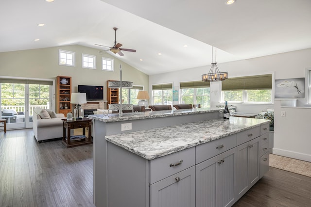 kitchen featuring gray cabinets, light stone counters, lofted ceiling, dark hardwood / wood-style floors, and a center island