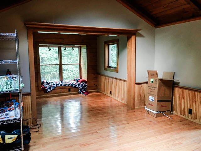 empty room with light hardwood / wood-style floors, wood walls, and lofted ceiling