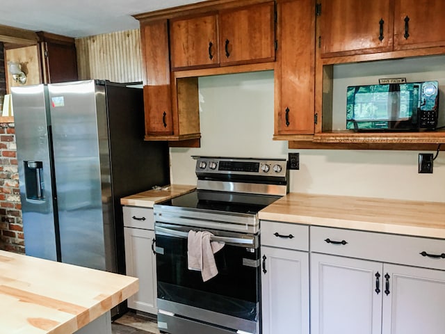 kitchen with stainless steel appliances, white cabinetry, and wood counters