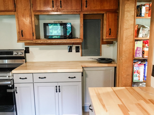 kitchen featuring stainless steel range, wooden counters, and white cabinetry