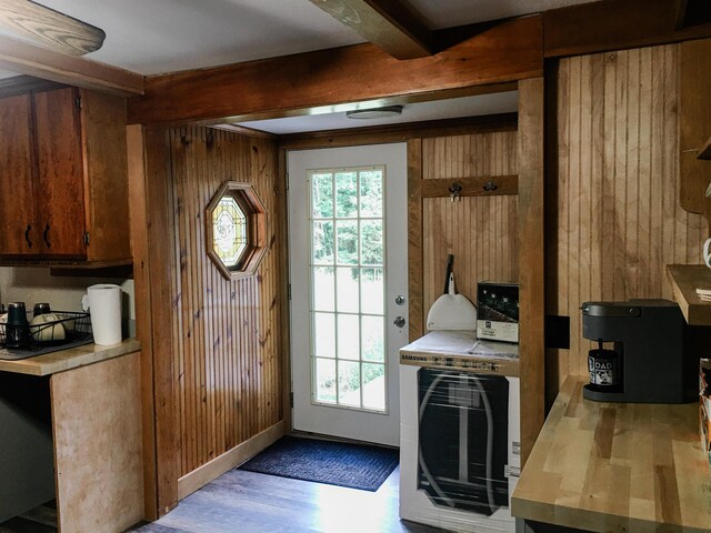 entryway featuring light wood-type flooring, beam ceiling, and wooden walls