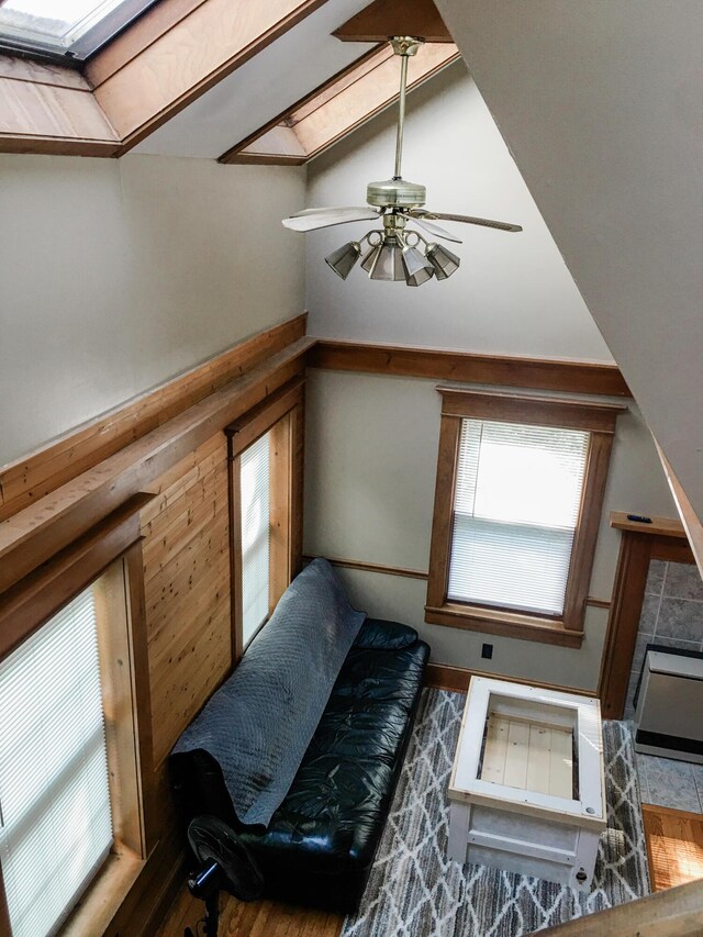 living area featuring vaulted ceiling with skylight, ceiling fan, and dark wood-type flooring