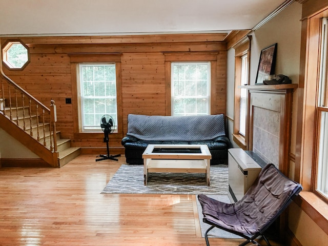 sitting room with a wealth of natural light, wood walls, light wood-type flooring, and crown molding