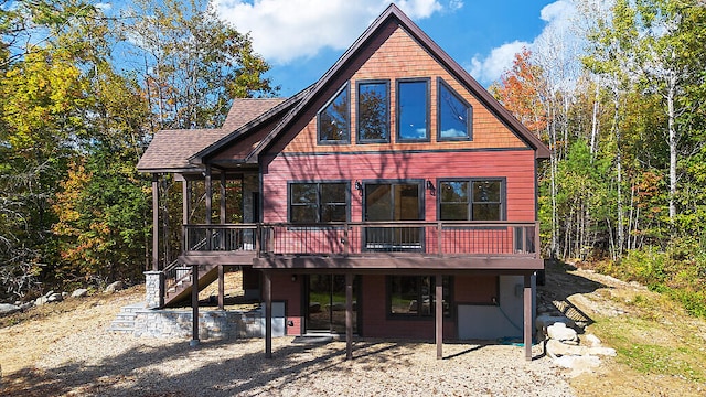 view of front facade with a shingled roof, stairway, and a deck