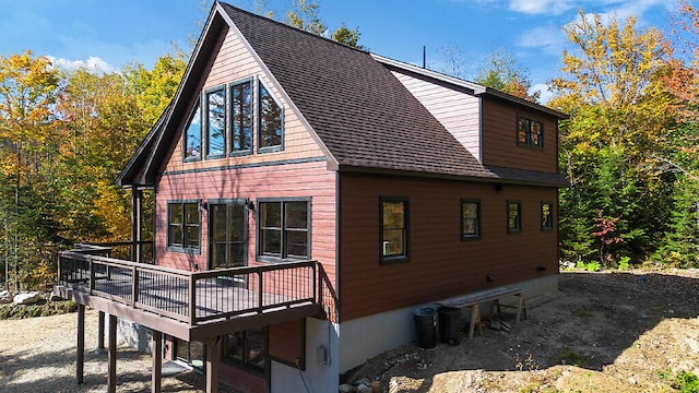 view of side of property with roof with shingles and a deck