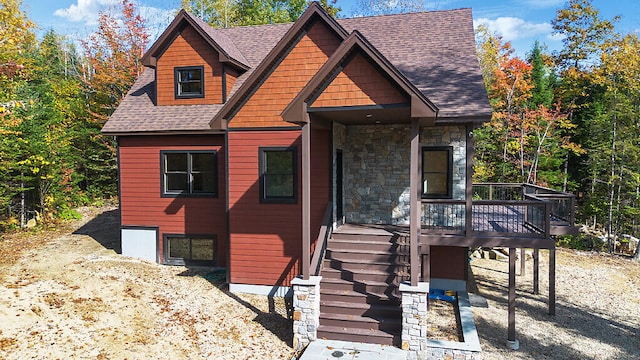 rustic home with stone siding, a shingled roof, stairway, and a deck