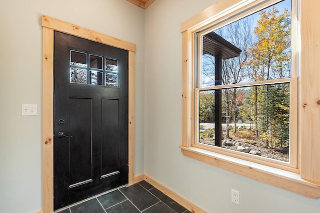 entrance foyer with dark tile patterned floors and baseboards