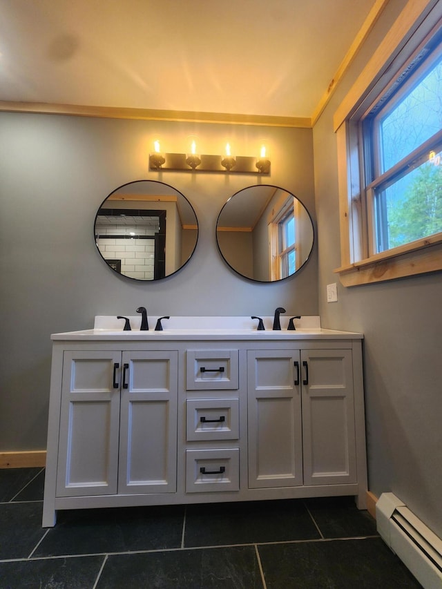 full bath with a baseboard radiator, a sink, baseboards, and double vanity