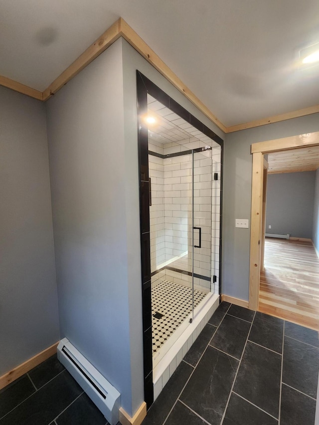 full bath with a stall shower, a baseboard radiator, tile patterned flooring, and baseboards