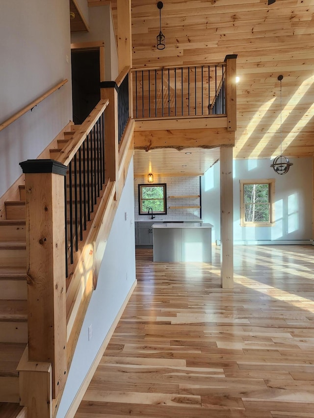 staircase with sink, an inviting chandelier, a towering ceiling, wood-type flooring, and wood ceiling