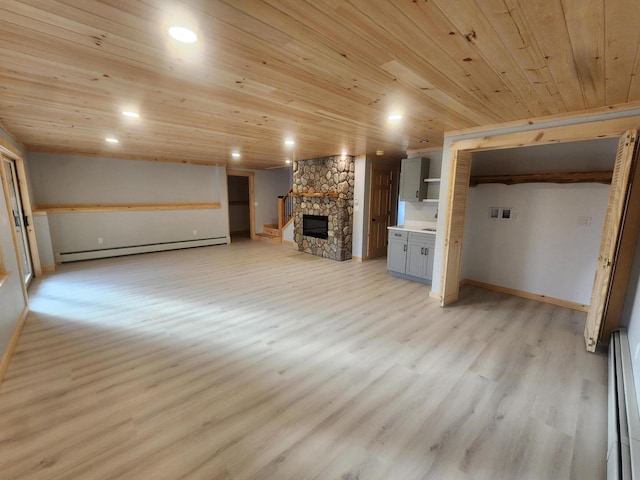 unfurnished living room with a stone fireplace, light hardwood / wood-style floors, wood ceiling, and a baseboard heating unit