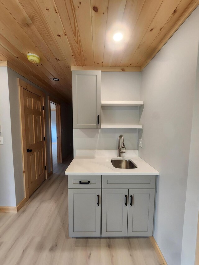 kitchen with gray cabinets, light wood-type flooring, sink, and wood ceiling