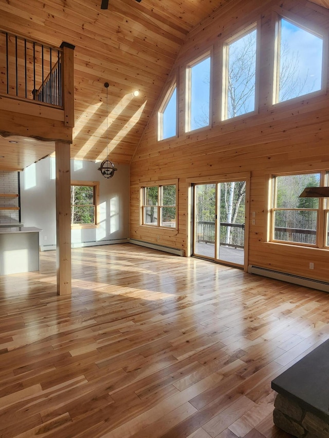 unfurnished living room featuring a wealth of natural light, light hardwood / wood-style flooring, high vaulted ceiling, and a baseboard heating unit