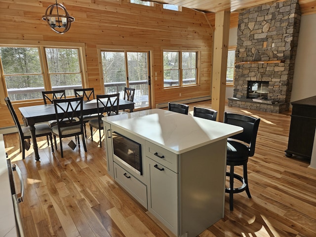 kitchen with built in microwave, a fireplace, wood walls, and light wood-style flooring