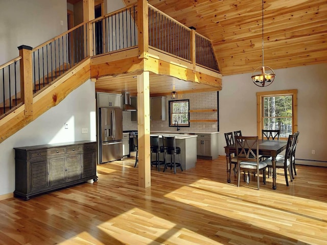 dining space with wood ceiling, high vaulted ceiling, stairs, light wood-style floors, and a chandelier