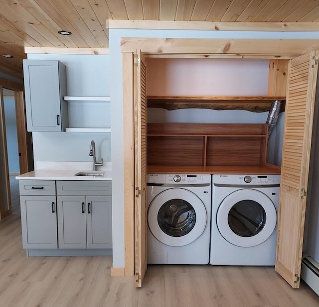 clothes washing area featuring laundry area, separate washer and dryer, a sink, wood ceiling, and light wood-type flooring