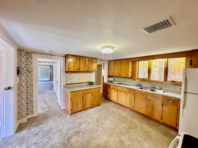 kitchen featuring light carpet, range, pendant lighting, white fridge, and sink