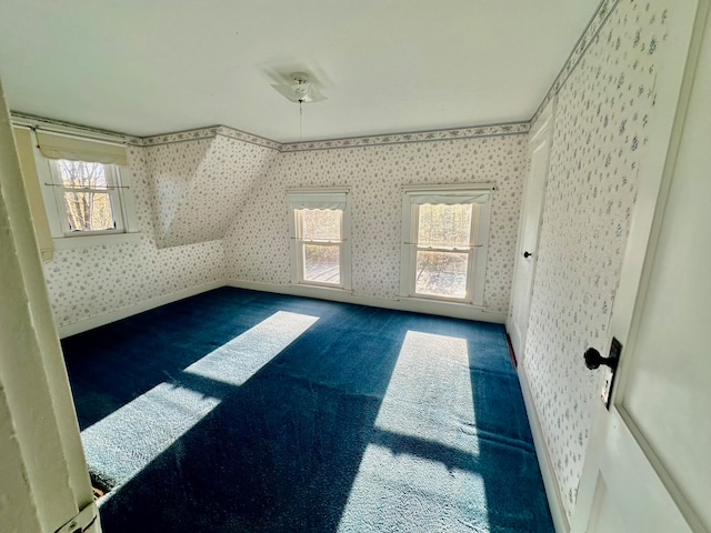 bonus room with dark carpet and plenty of natural light